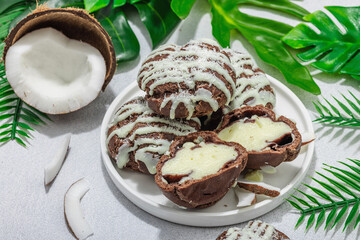 Profiteroles choux pastry buns with coconut cream served in tropical style. Palm leaves
