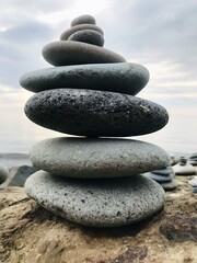 Balanced pebbles pyramid on the beach on sunny day and clear sky at sunset