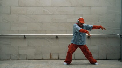 Handsome choreographer practice street dance in gray background. Young attractive b-boy dancer...