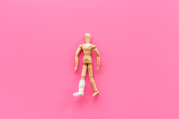 Wooden dummy man with leg broken - leg in bandage. Medical insurance and healthcare concept