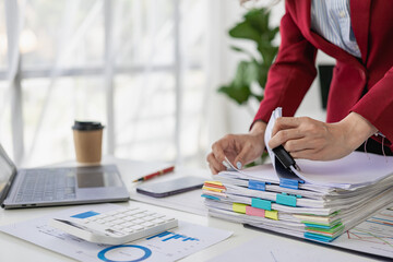 Close-up of business woman or accountant working using laptop computer to analyze business report graphs and financial charts to check company finances, income and monthly expense budget.