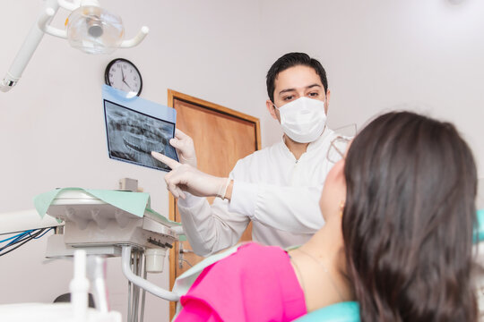 Dentist showing and explaining a dental x-ray to his patient in the dental office.