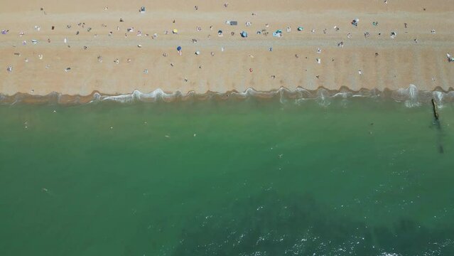 A high angle drone shot of the beach with emerald ocean waters.