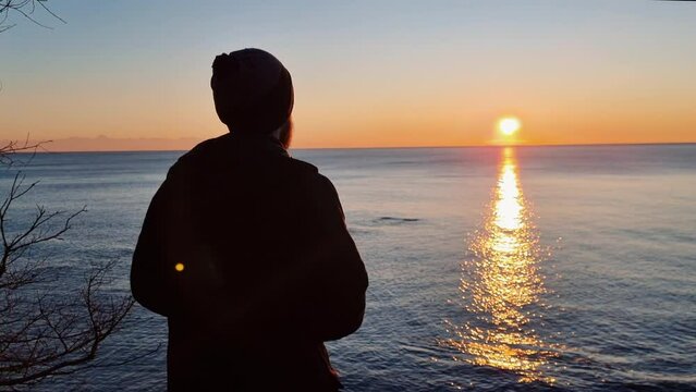 Man on a beach is looking distance during sunset. Person contemplates the beauty of nature.