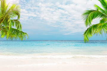 Beautiful white sand beach with turquoise water, coconut palm trees and blue sky with clouds in...