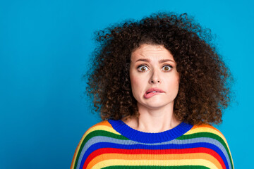 Photo portrait of pretty young girl nervous frightened bite lips wear trendy rainbow print outfit isolated on blue color background