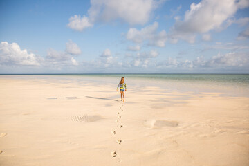 child walking with single set of footprints on a beach