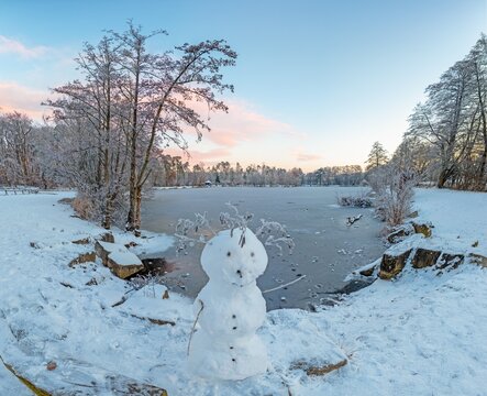 Picture over a frozen lake in the morning light with a snowman