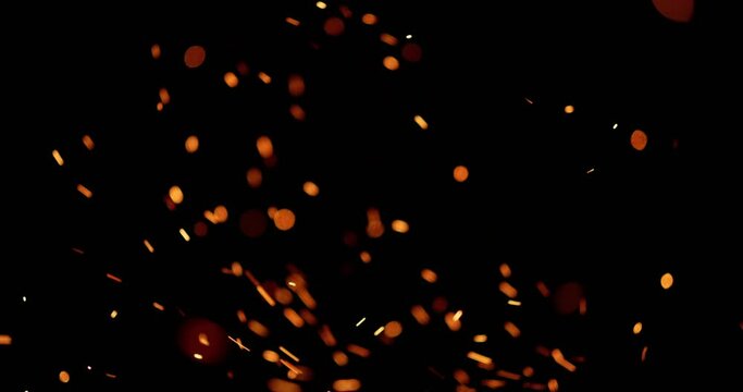 Close-up. Darkness is diluted by swirling small bright sparks, they burst out of yellow tongues of flame, and circle in dark space like hundreds of small fireflies. Cinematic AD. Template for title.