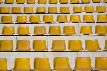 Rows of yellow empty seats in an outdoor bleacher on a sunny day. Theater and sports in the open...