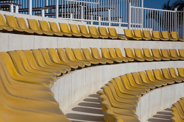 Rows of round stands with yellow outdoor seats for concerts and sports. Outdoor seating for...