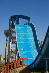 Water slide with sharp descent and ascent in an outdoor water park. Steep slide with a high degree...