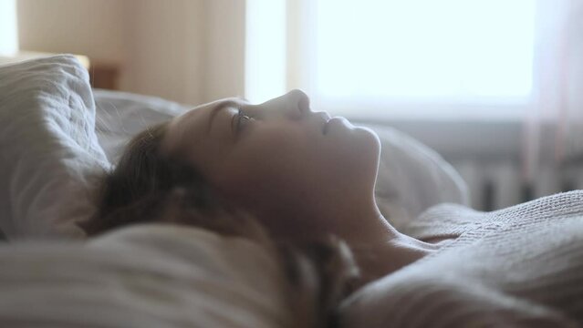 Portrait of sad young woman laying on bed suffering from depression anxiety loneliness or mental health problem at home Thoughtful female upset feeling stress and pressure indoors
