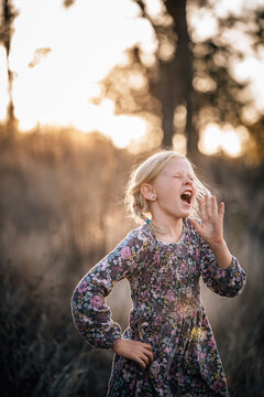 Girl with her hand upto her face singing into the distance