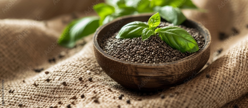 Poster basil seeds placed in a tiny bowl on a burlap surface.