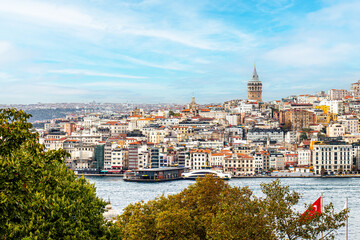Fototapeta na wymiar The Galata Tower looms over the dense, colorful buildings of Istanbul's skyline, with the bustling Bosphorus in the foreground, encapsulating the city's vibrant urban life.