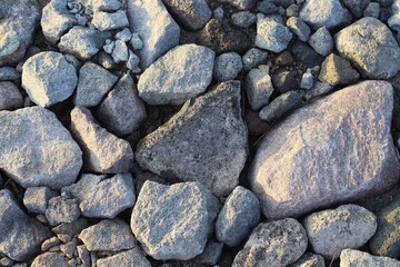 Large stones of different shapes on the riverbank close-up. there are a lot of small stones nearby.