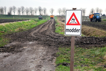 Verkeersbord met waarschuwing tijdens het oogsten in de agrarische sector. Door de modder wat door...