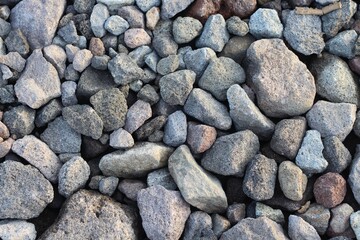 Large stones of different shapes on the riverbank close-up. there are a lot of small stones nearby.
