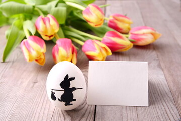 Tulips and easter egg with card, on wooden background.
