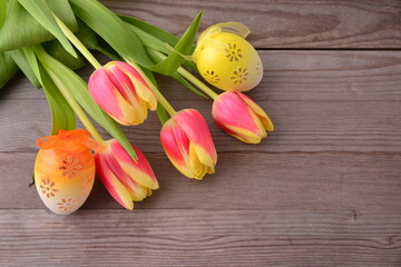 Easter card with easter eggs and tulips on wooden background.