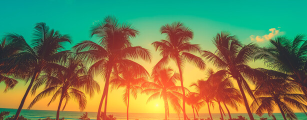Fototapeta na wymiar Silhouetted palm trees against a vibrant tropical sunset. Wide banner with copy space.
