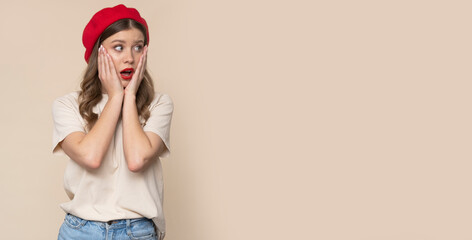 Shocked young woman on light brown background.