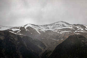 Beautiful mountain landscape. Clouds in the sky. Green grass. Snow on mountain peaks.
