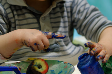Main enfant dans la peinture. Garçon jeune jouant à la peinture, doigt et main sales, loisirs...