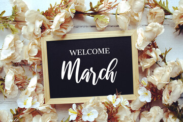 Welcome March text message with flower decoration on wooden background