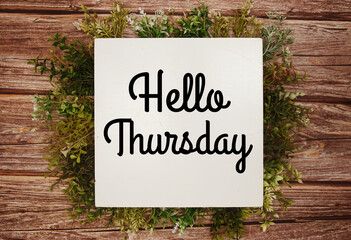 Hello Thursday text message with green leaves decoration on wooden background