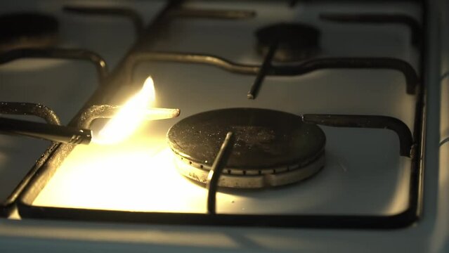 Kitchen gas burner turning on with blue cooking flame.