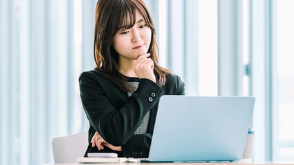 パソコンを使いながら悩むビジネスウーマン