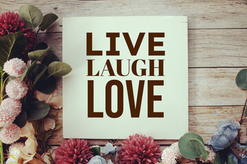 Live Laugh Love texrt message with flower decoration on wooden background