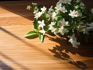 Wooden table with white jasmine flowers and green leaves