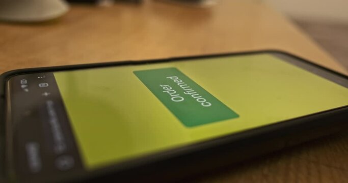 Pressing the Pay Now button on the smartphone screen. Order confirmed, response to purchase of goods, concept of online payment, online store. Close-up, side view.