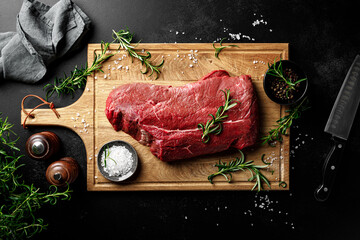 Beef meat entrecote on a cutting board, raw beef meat fillet on black background, top view
