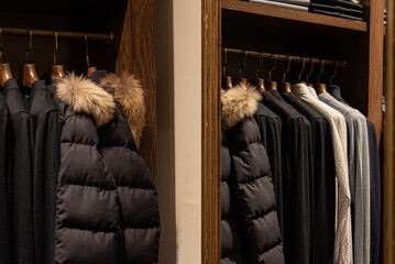 wardrobe with men's clothes in dark colors. jacket, down jacket, shirt. The clothes are neatly hung...