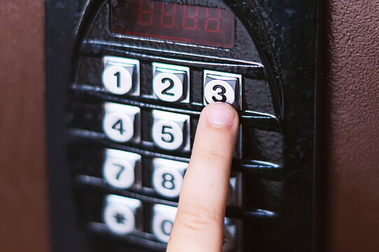 Close-up of a little girl's hand entering a security code. A little girl presses a button on the intercom panel. The child enters the door code into the combination lock and calls the intercom. Safety