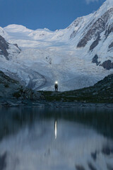 Zdjęcie turysty który maszeruje po zmroku na tle lodowca - 726634224