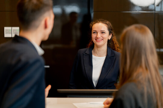 The receptionist at the counter meets guests with luggage in the hotel business travel hospitality