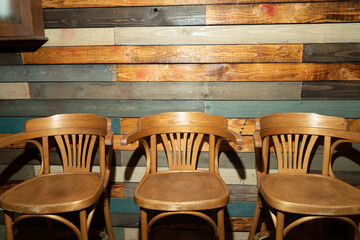 Three wooden chairs stand against the wall