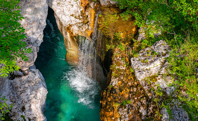 Little cascade falling into Soča (Emerald River) in Slovenia, pristine wild alpine river with...