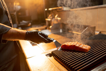 close-up of a chef holding an appetizing juicy fried piece on a spatula in a restaurant kitchen
