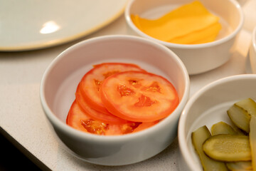 close-up of lettuce onion and tomato for making a burger stand in plates on the table in the kitchen