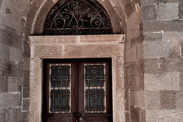 Fototapeta na wymiar old stone building entrance door made of wood, brown painted, metall shutters and frame