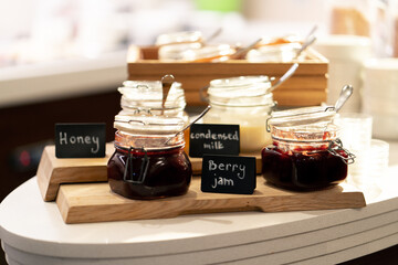 close-up breakfast buffet line serving a variety of jams in a hotel with hospitality signs
