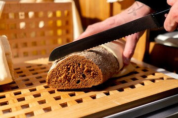 a buffet line in a hotel restaurant, a guest cuts bread with a knife during continental breakfast