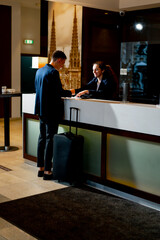 The receptionist at the counter meets the guest with luggage in the hotel business travel...
