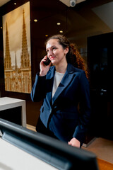 The porter stands at the counter, speaks on the phone and informs the guest about the arrival of the taxi